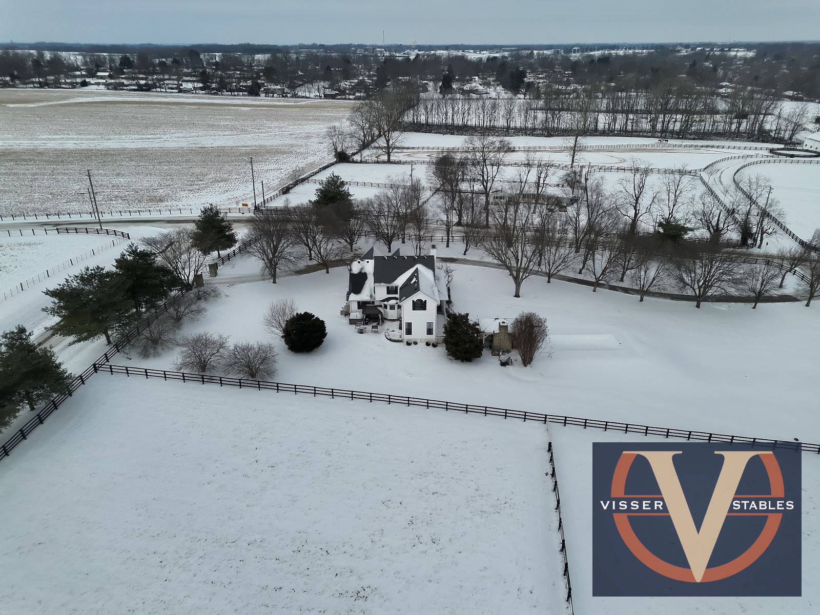 Aerial view of a farmhouse and pastures, with Visser Stables watermark